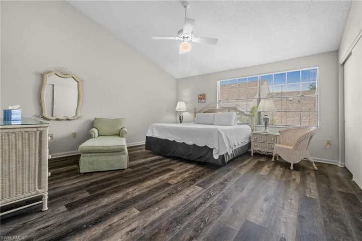 Bedroom featuring wood finished floors, vaulted ceiling, a ceiling fan, and a textured ceiling