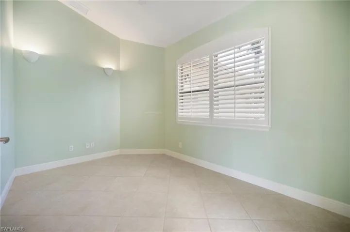 Tiled spare room featuring lofted ceiling and baseboards