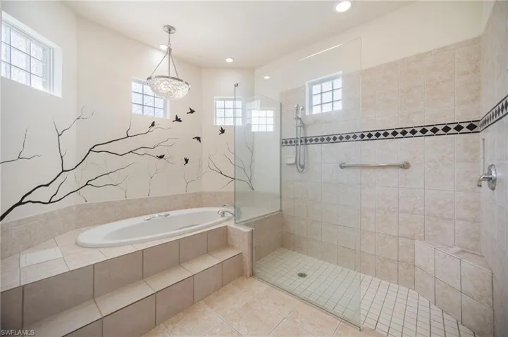 Full bath featuring tiled shower, a garden tub, and a healthy amount of sunlight