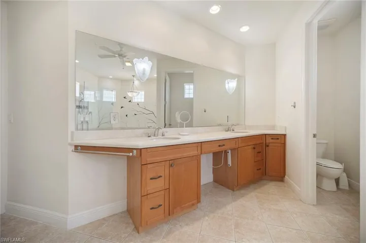 Full bathroom featuring double vanity, walk in shower, baseboards, and a sink