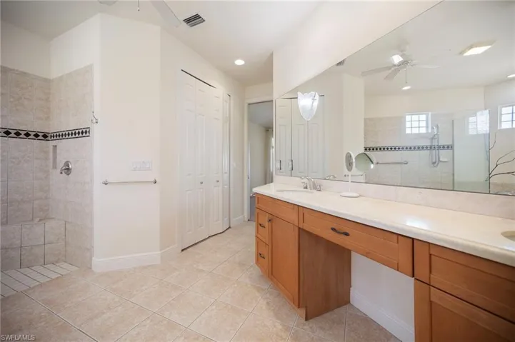Full bathroom featuring a ceiling fan, visible vents, a walk in shower, and a sink