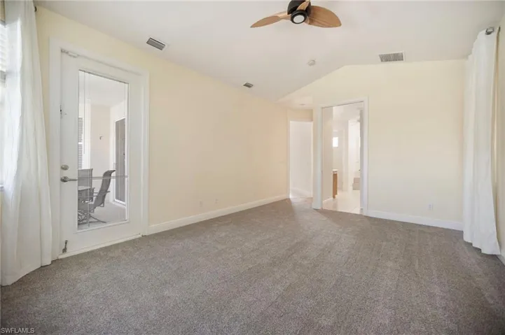 Primary room featuring lofted ceiling, a ceiling fan, visible vents, and baseboards