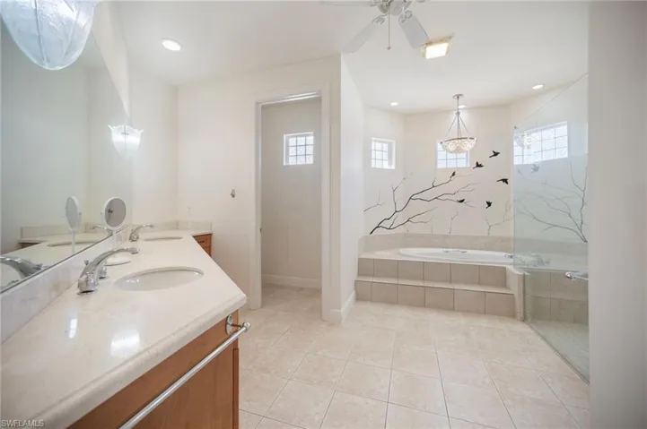 Ensuite featuring tile patterned flooring, a bath, a ceiling fan, and a sink