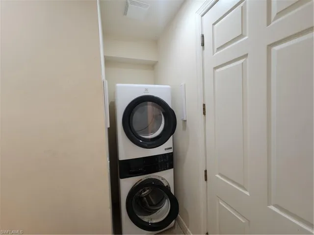 Washroom featuring stacked washer and dryer, visible vents, and laundry area