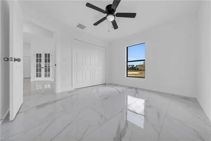Unfurnished bedroom with light marble finish floors, a ceiling fan, and a closet