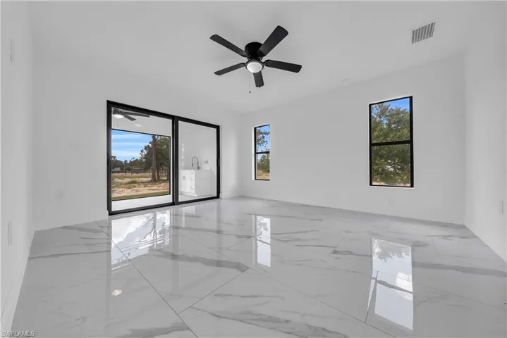 Empty room featuring light marble finish floors and ceiling fan