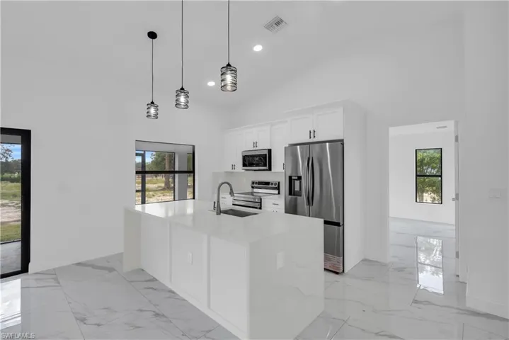 Kitchen with appliances with stainless steel finishes, light stone countertops, recessed lighting, decorative light fixtures, and white cabinets