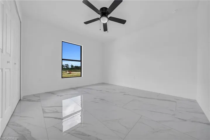 Empty room with light marble finish flooring and ceiling fan
