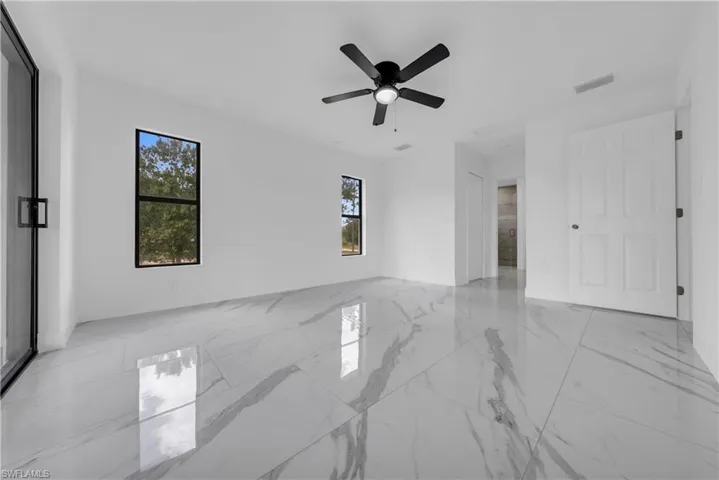 Spare room with light marble finish floors and ceiling fan