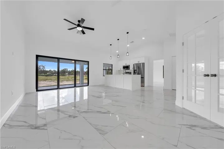 Living area featuring light marble finish flooring, high vaulted ceiling, ceiling fan, and recessed lighting