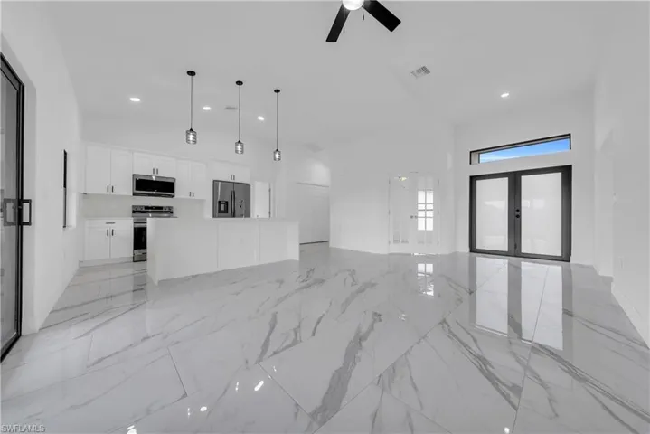 Unfurnished living room with french doors, light marble finish floors, recessed lighting, a high ceiling, and ceiling fan