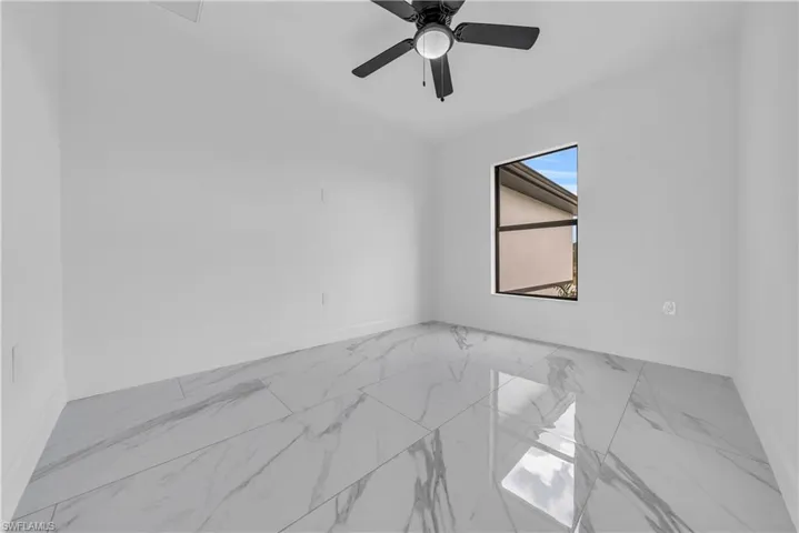Empty room featuring marble look tile flooring and baseboards