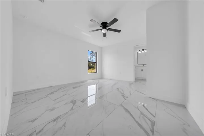 Unfurnished room featuring light marble finish flooring and a ceiling fan