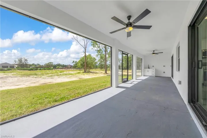 Unfurnished sunroom with a patio, unfinished concrete floors, and ceiling fan