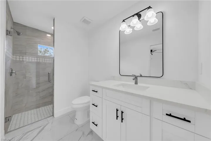 Full bathroom featuring a stall shower, vanity, light marble finish floors, and recessed lighting