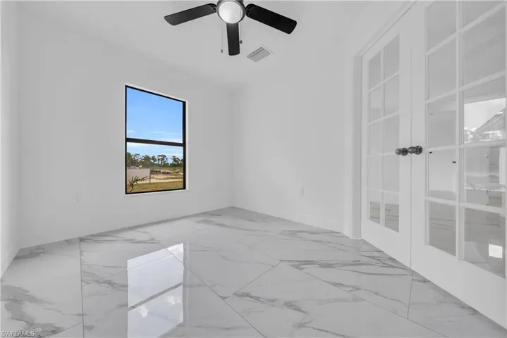 Empty room featuring light marble finish floors and french doors