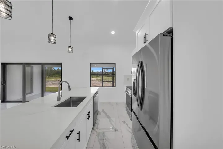 Kitchen featuring white cabinetry, decorative light fixtures, appliances with stainless steel finishes, light stone countertops, and recessed lighting