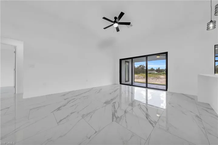 Spare room featuring light marble finish floors, lofted ceiling, and ceiling fan