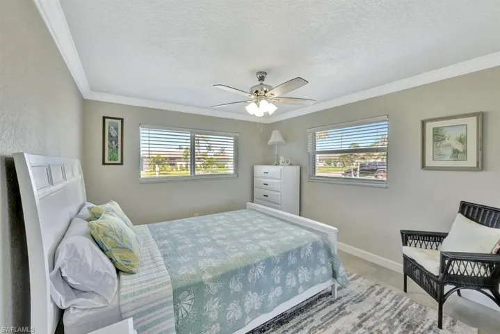 Bedroom with ceiling fan, ornamental molding, and a textured ceiling