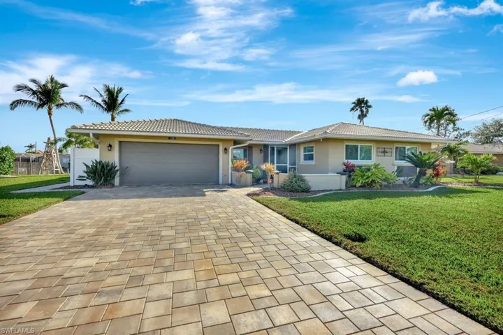 Single story home with a garage and a front lawn