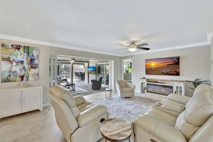 Living room with crown molding, ceiling fan, and a wealth of natural light