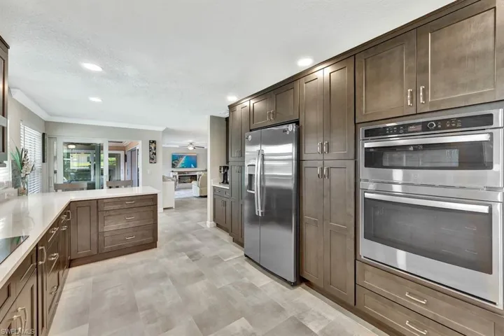 Kitchen with dark brown cabinetry, crown molding, a textured ceiling, appliances with stainless steel finishes, and ceiling fan