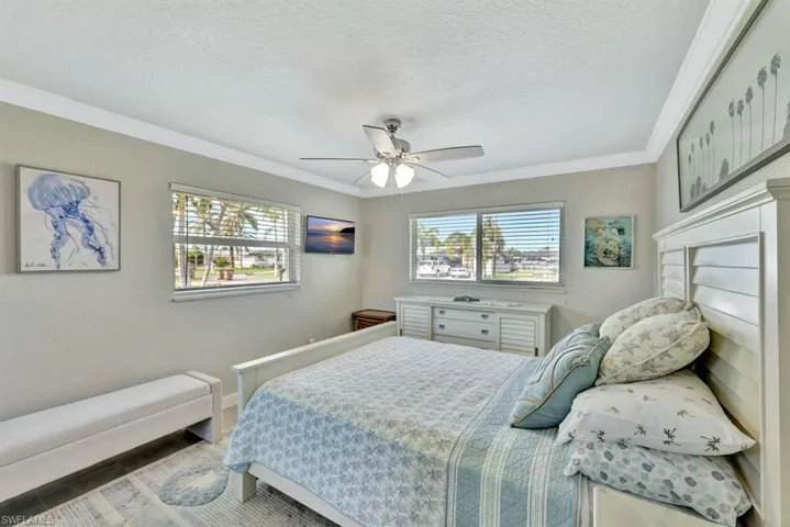 Bedroom with ornamental molding, a textured ceiling, and ceiling fan