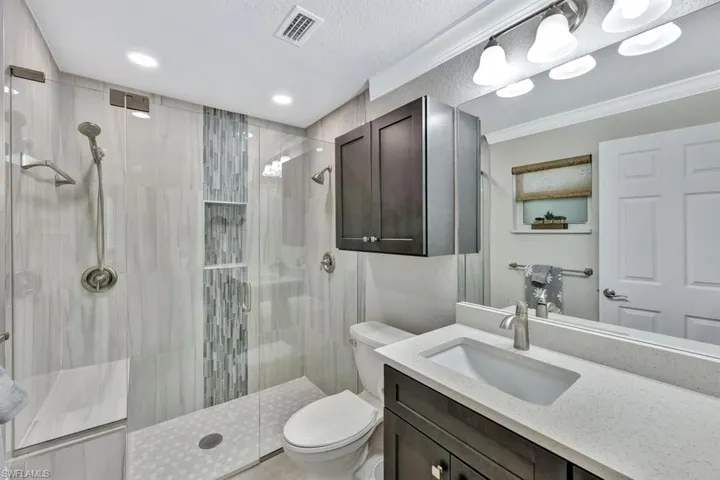 Bathroom with vanity, ornamental molding, toilet, and walk in shower