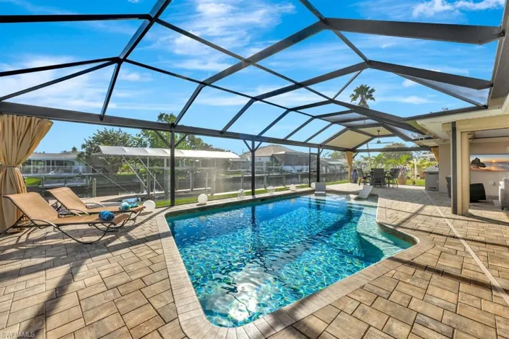 View of pool with a patio and glass enclosure