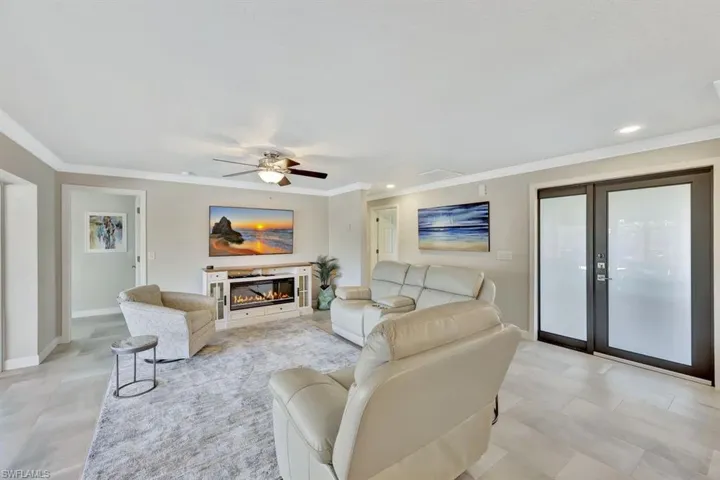 Living room with crown molding, ceiling fan, and french doors