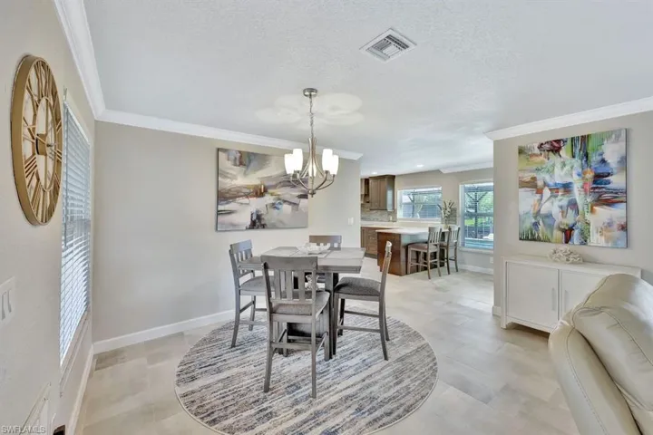 Dining room featuring an inviting chandelier, crown molding, and a textured ceiling