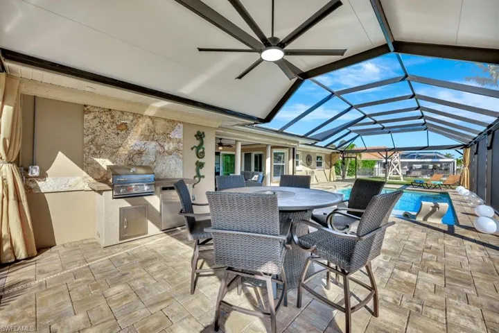 View of patio with exterior kitchen, ceiling fan, area for grilling, and glass enclosure Custom covered extended Laniai area