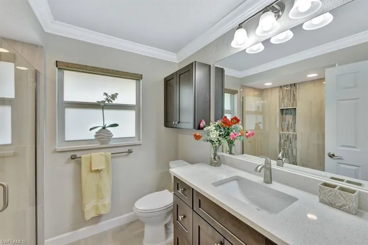 Bathroom featuring an enclosed shower, vanity, crown molding, and toilet