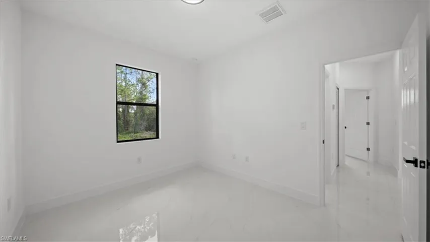 Unfurnished bedroom featuring marble finish flooring and baseboards
