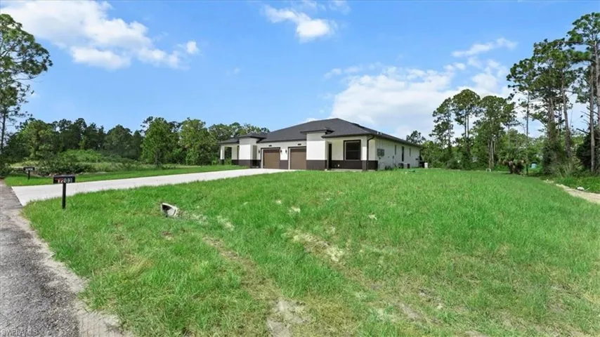 Prairie-style house with driveway, a garage, a front lawn, and stucco siding