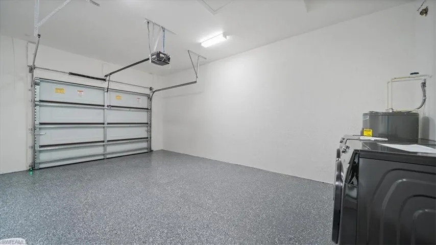 Garage with water heater, a garage door opener, and washing machine and dryer
