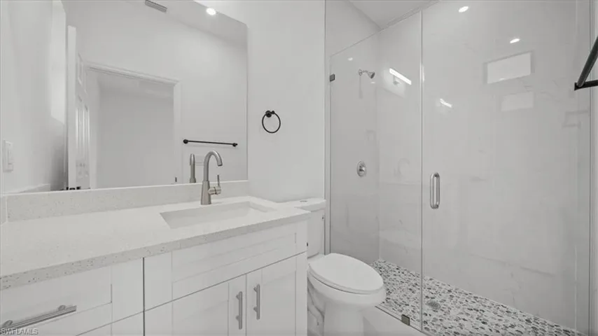 Bathroom featuring a marble finish shower, vanity, and recessed lighting