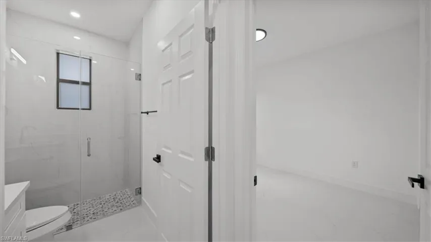 Bathroom featuring a marble finish shower, vanity, and marble look tiles