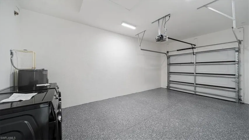 Garage featuring washer / dryer, a garage door opener, and water heater