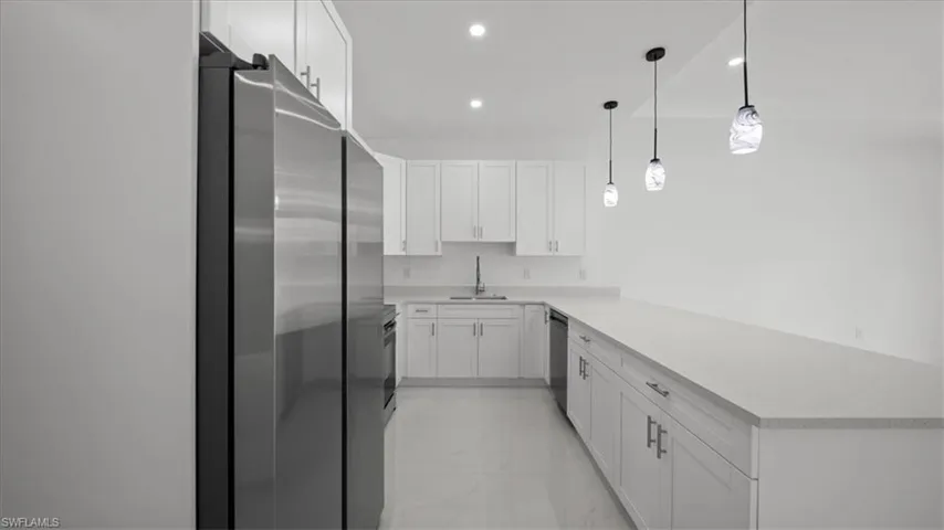 Kitchen featuring stainless steel appliances, a peninsula, light countertops, recessed lighting, and light marble finish floors