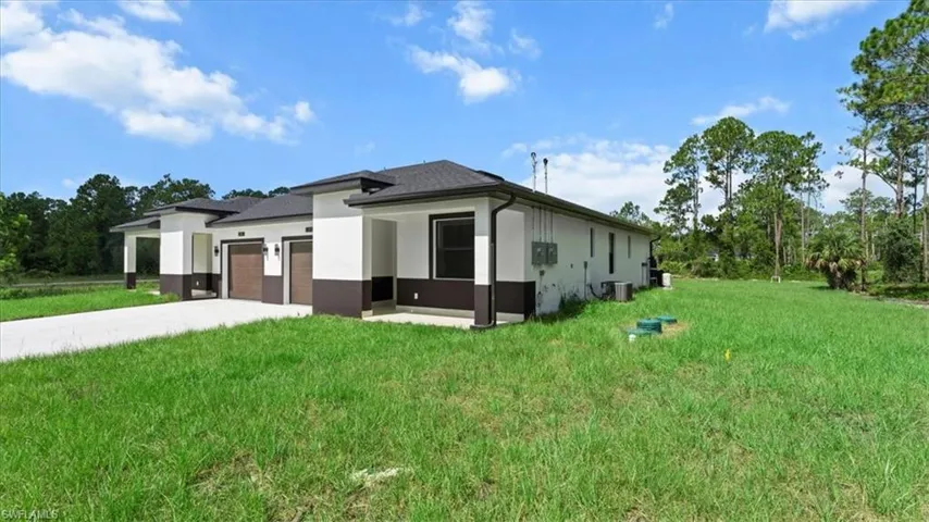 View of side of property featuring stucco siding, a lawn, driveway, and an attached garage