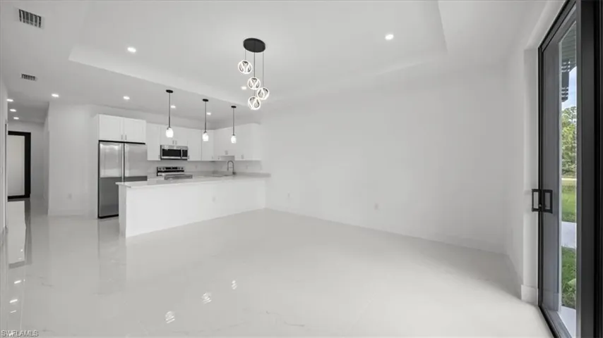 Kitchen featuring stainless steel appliances, recessed lighting, white cabinetry, light countertops, and a raised ceiling