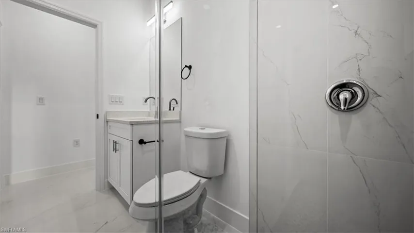 Bathroom with vanity, marble finish floors, and a marble finish shower