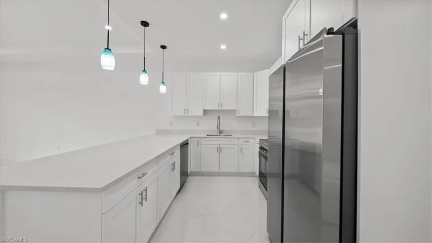 Kitchen with stainless steel appliances, white cabinetry, light countertops, and recessed lighting