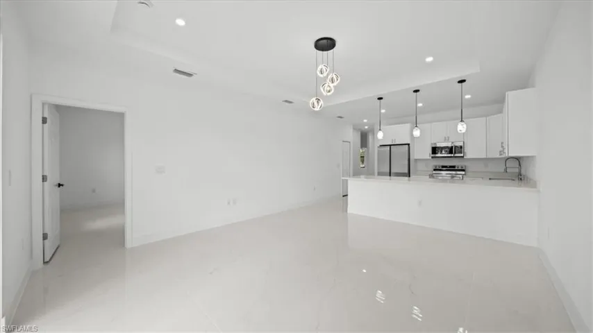Kitchen featuring recessed lighting, stainless steel appliances, white cabinets, and light marble finish flooring
