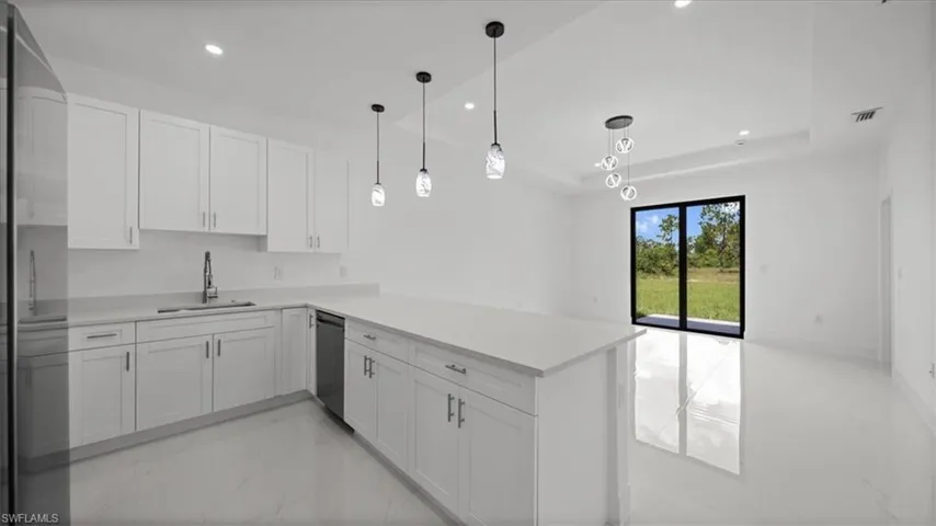 Kitchen featuring stainless steel fridge, light marble finish flooring, light countertops, open floor plan, and recessed lighting