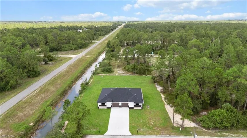 Aerial view of property and surrounding area with a forest