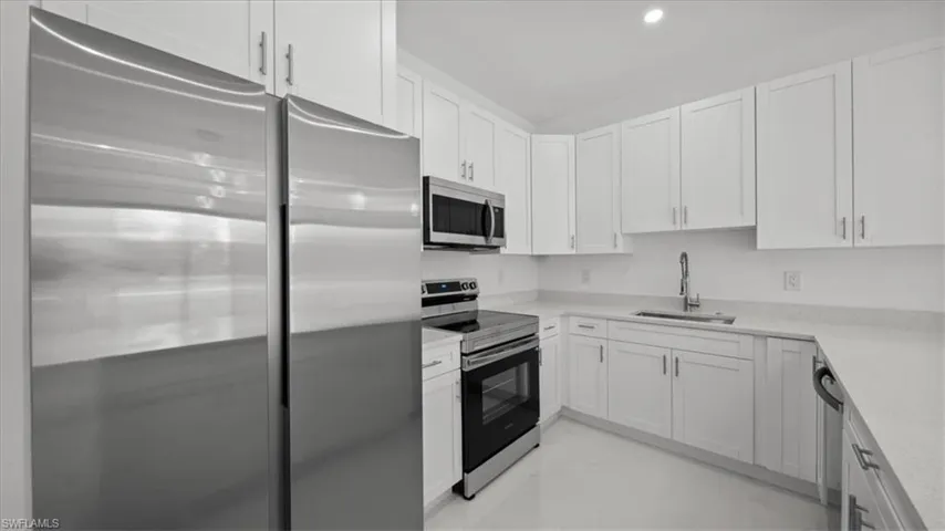 Kitchen featuring appliances with stainless steel finishes, white cabinets, and light countertops