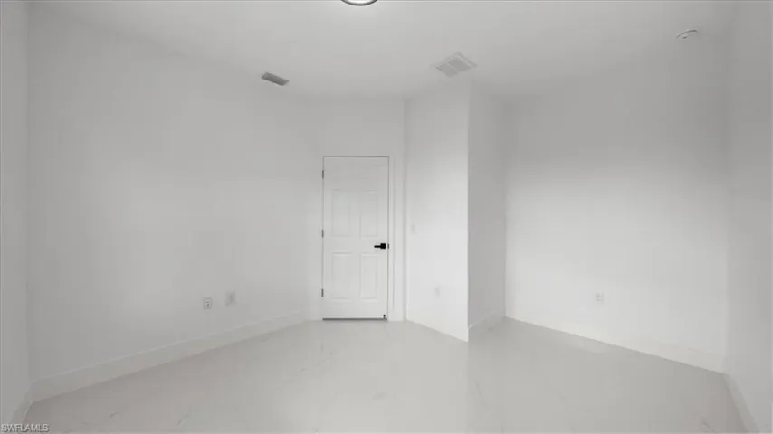 Empty room featuring light marble finish floors and baseboards