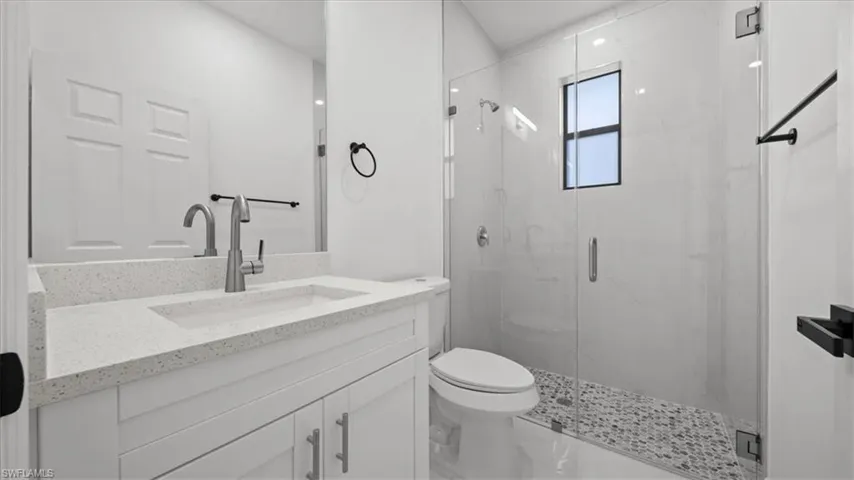 Bathroom featuring vanity and a marble finish shower